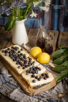 a piece of bread with blueberries and lemons on it next to some flowers