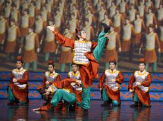 a group of people standing on top of a stage with dancers in front of them