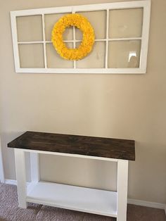 a wooden bench sitting in front of a window with a wreath on the wall above it