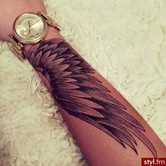 a woman's arm with a watch on top of it and an angel wing tattoo