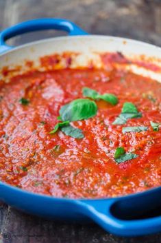 a blue pan filled with tomato sauce and basil