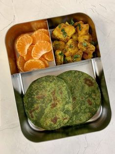 a metal container filled with food on top of a white counter next to an orange slice