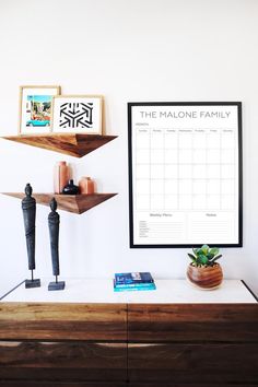 a wooden shelf with a calendar on it next to a potted plant and other items