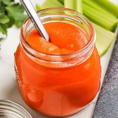 a jar filled with carrots and celery on top of a white table