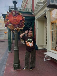 a woman standing next to a lamp post with a pumpkin on it's shirt