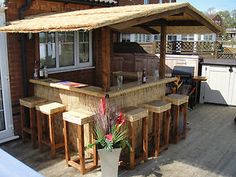 an outdoor bar with stools and a potted plant on the outside patio area