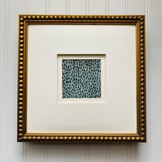 a white and gold frame hanging on the wall