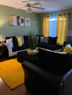 a living room with black couches and yellow rugs