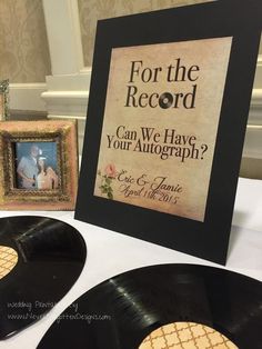 two black record records sitting on top of a table next to a framed photo and an album