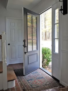 an entryway with a rug and two doors leading to the outside area, one door is open