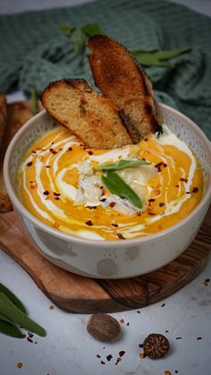 a white bowl filled with carrot soup and toast