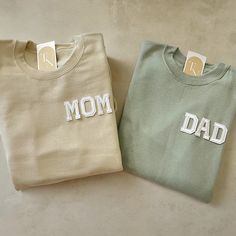 two sweatshirts with the word mom and dad printed on them sitting next to each other