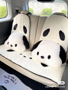 two panda bears are sitting in the back seat of a car with pillows on it