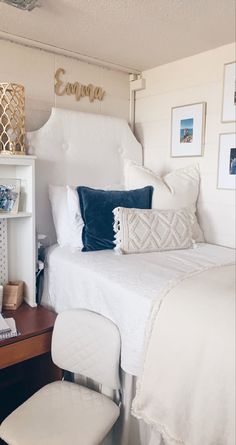 a white bed sitting in a bedroom next to a wooden desk and chair with pictures on the wall