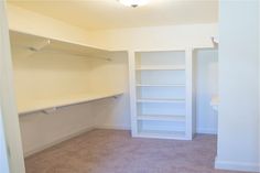 an empty closet with white shelving and carpeted flooring is shown in this image