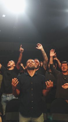 a group of men standing next to each other in front of a crowd holding their hands up