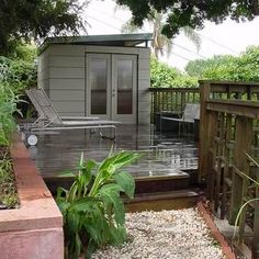 a wooden deck with steps leading up to a small shed on the side of it