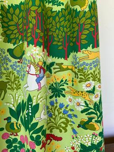 the curtain is open to show an image of trees and animals on green fabric with white background