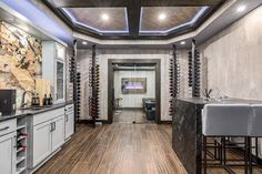 a kitchen with marble counter tops and white cabinets, along with wine racks on the wall