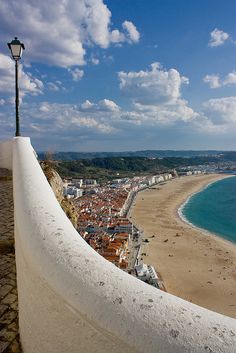 a view from the top of a building looking down at a beach and ocean with buildings in the distance