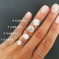 a woman's hand with three different rings on it and four carats in the middle