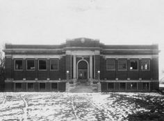 an old black and white photo of a building with snow on the ground in front of it