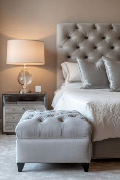 a white bed sitting next to a night stand with a lamp on top of it