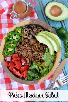 a bowl filled with meat and vegetables next to an avocado