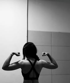 a woman standing in front of a bathroom mirror holding her arms up to the side