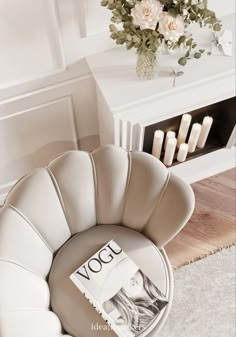 a white chair sitting in front of a fireplace next to a vase filled with flowers