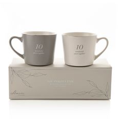 two grey coffee mugs sitting on top of a box with the words mr and mrs