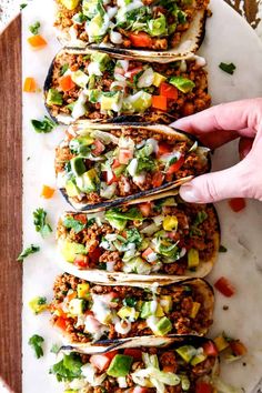 a person reaching for some tacos on a plate