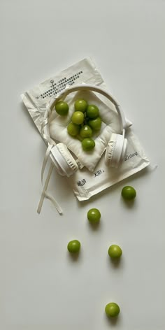 some green olives are in a bag on a white surface and scattered around them