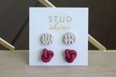 two red and white knot earrings sitting on top of a card