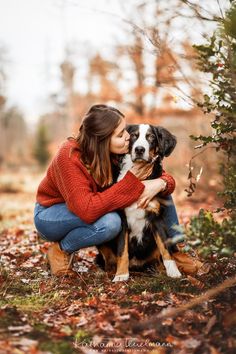 a woman kneeling down with her dog in the woods for a photo shoot at fall