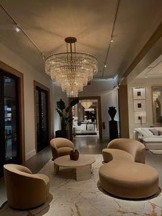 a living room filled with lots of furniture and a chandelier hanging from the ceiling