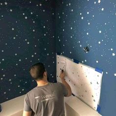 a man is painting stars on the wall in a bathroom with blue and white walls