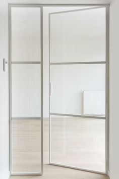 an empty room with white walls and wooden floors is seen through the glass sliding doors