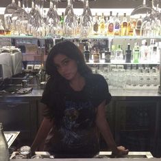 a woman sitting at a bar with lots of liquor bottles in the backgroud