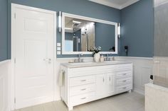 a bathroom with blue walls and white cabinets