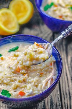 a spoonful of chicken and rice soup in a blue bowl with lemons on the side