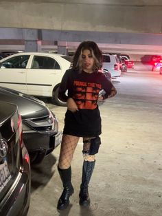 a woman standing next to parked cars in a parking lot with her hands on her hips