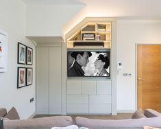 a man and woman are kissing in front of a flat screen tv on the wall