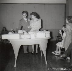 an old black and white photo of people at a table with cake on it,