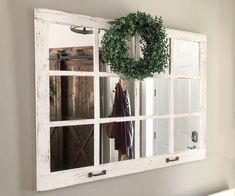 an old window is hung on the wall with a wreath hanging from it's side