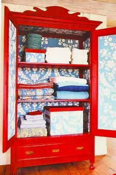 a red china cabinet with blue and white wallpaper