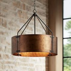 a chandelier hanging from a brick wall in a living room with large windows