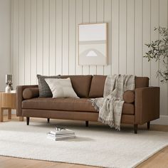 a living room with a brown couch and white rug