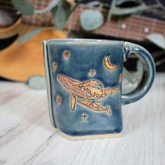 a ceramic mug with an image of a whale on it's side sitting on a table