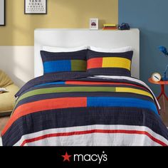 a bed room with a neatly made bed and colorful bedspread on the wall